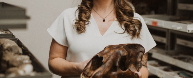 Kallie Moore hold a fossil with very long teeth