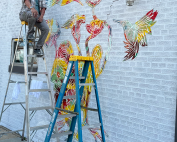 Richie Morales on a ladder next to the developing mural
